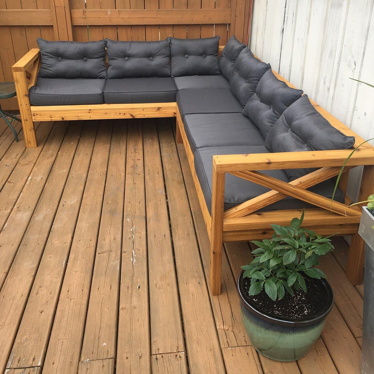 Wooden patio sectional with cushions on a backyard deck